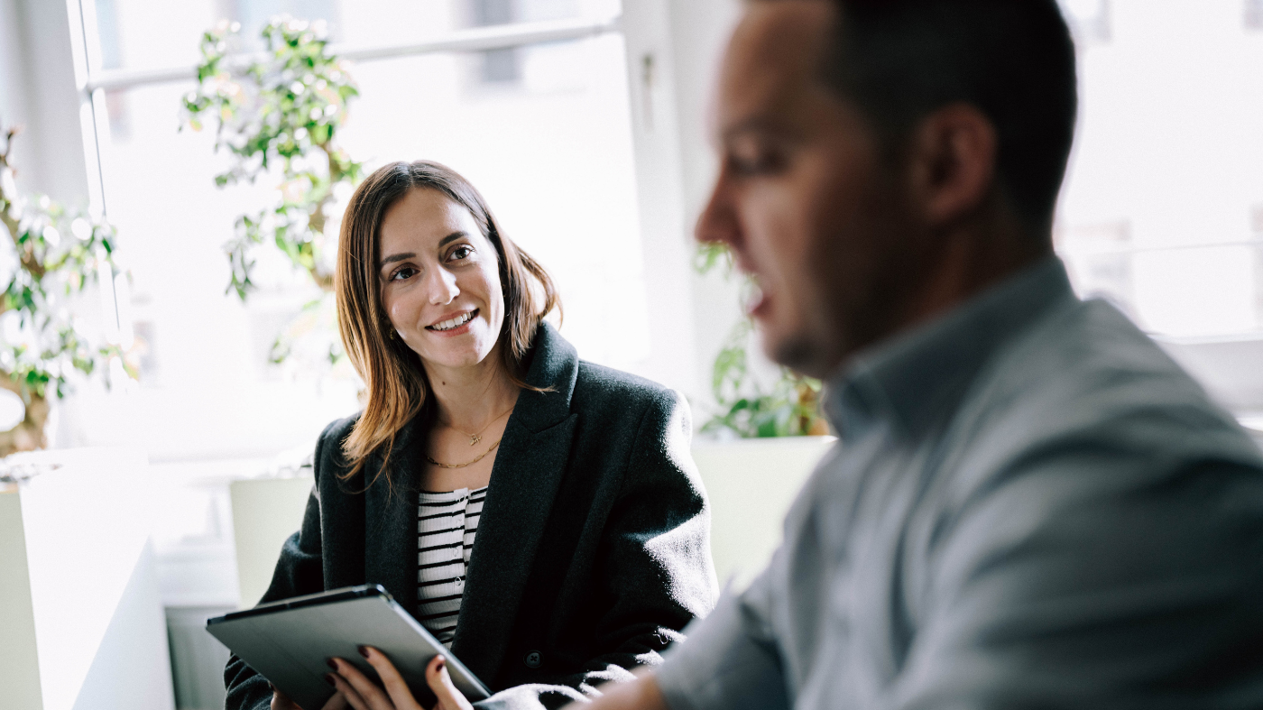 So wird Ihr Newsletter zum Erfolg! Mitarbeiter sitzen im Gespräch an einem Schreibtisch