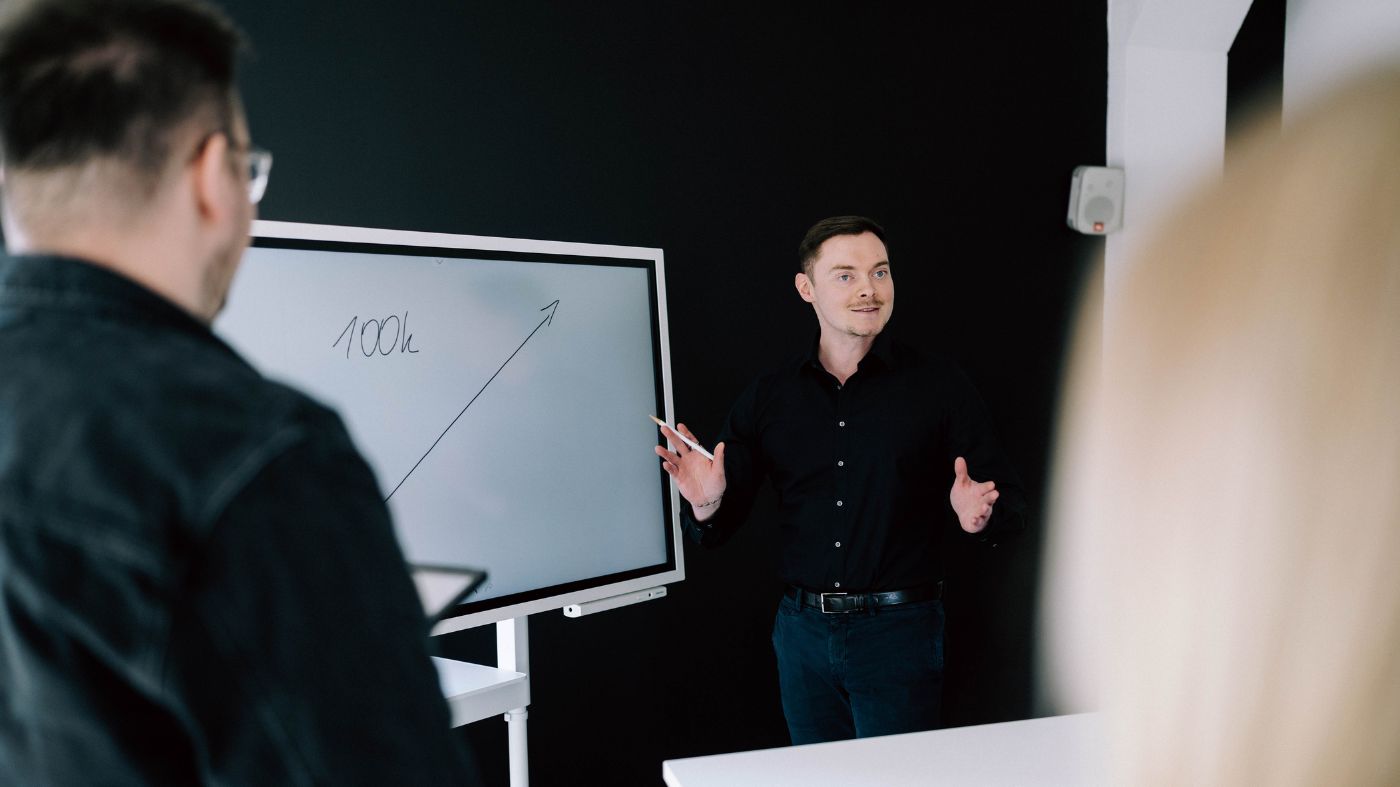 Erläuterungen von Google ads Mitarbeiter steht vor einem Bildschirm und Präsentiert