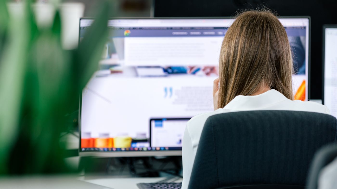 Webseite Usability Webdesignerin sitzt vor zwei großen Monitoren und arbeitet am Computer.